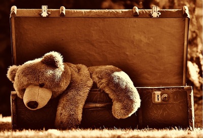 A teddy bear lying on a suitcase